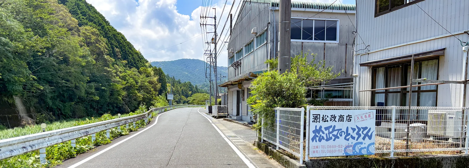 道路沿いに立つ「松政のところてん」の看板と社屋